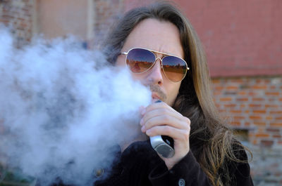 Portrait of young man smoking electronic cigarette 