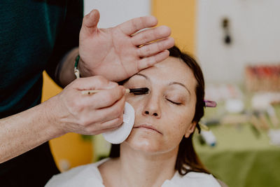 Midsection of man applying make-up for woman 