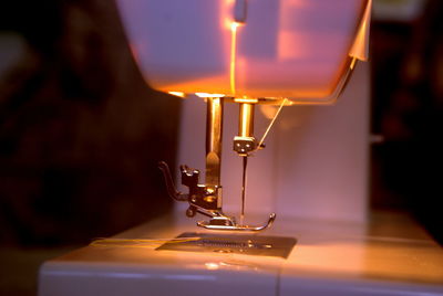 Close-up of illuminated sewing machine in darkroom