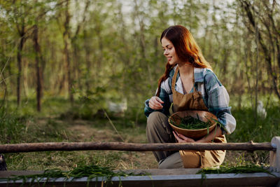 Smiling woman putting grass in chicken hoop