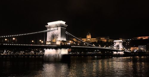 Illuminated bridge over river at night