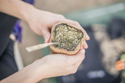 Close-up of person holding marijuana in container