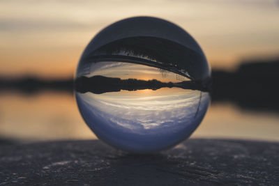 Close-up of crystal ball on beach during sunset