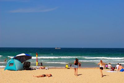 People on beach against clear sky