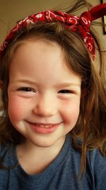 Close-up portrait of happy girl wearing red bandana at home