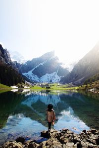 Rear view of man looking at lake against mountain