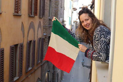 Portrait of woman holding flag while standing in balcony