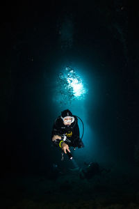 Man with illuminated lighting equipment in water at night