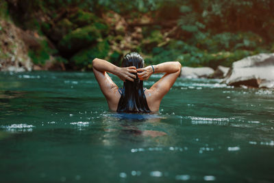 Young latina woman swimming in rio fortuna in costa rica with totally wet long hair