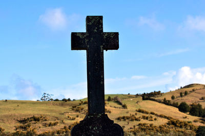 Cross in cemetery against sky