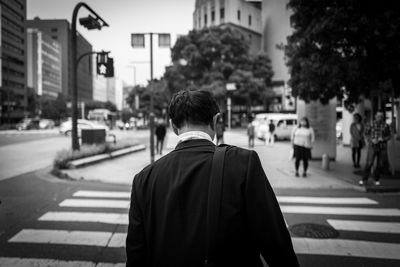 Rear view of men walking on road in city