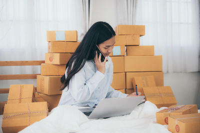 Young woman using mobile phone in box