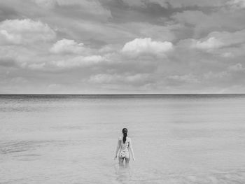 Rear view of woman standing in sea against sky
