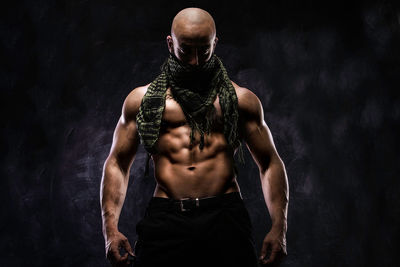Bald muscular man standing against black background