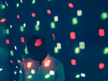 Young man standing against in darkroom with lights