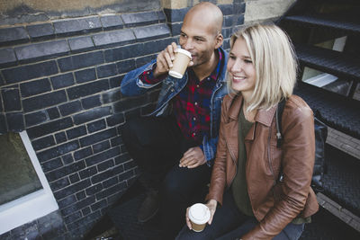 Couple having coffee while sitting on steps