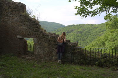 Rear view of woman standing by old ruin against sky