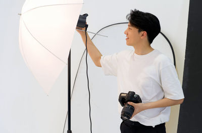 Photographer setting lighting equipment while holding camera