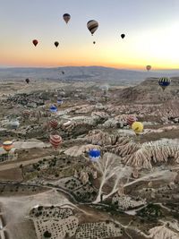 Hot air balloons flying over land during sunset