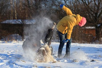 Boy and woman playing on snow during winter