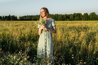 Portrait of young woman standing on field