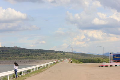 Man on road amidst land against sky