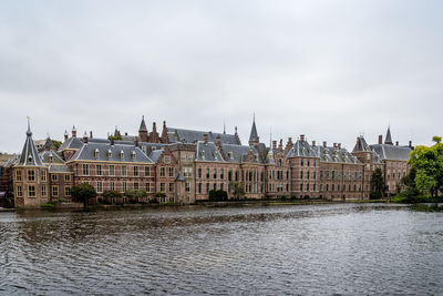 Binnenhof by hofvijver lake against cloudy sky