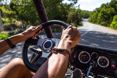 Midsection of man driving golf cart on road