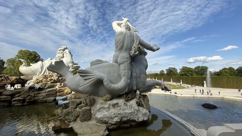 Statue by lake against sky