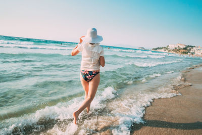 Rear view of woman standing at beach