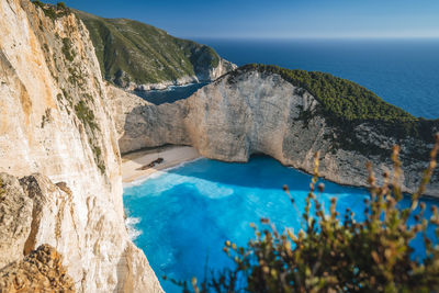 Scenic view of sea by rock formation against sky