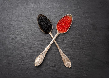 Grainy caviar of paddlefish fish and red chum salmon caviar in a spoon, black background, top view