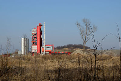 Factory on field against clear blue sky