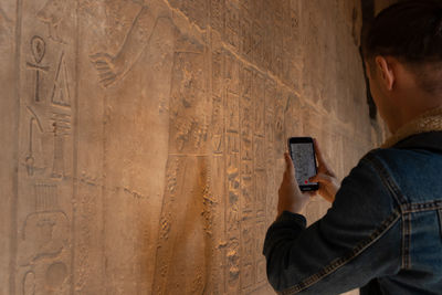 Close up view of young tourist man recording a video for social media to the hieroglyphics inside