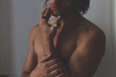 Close-up of shirtless man touching hand