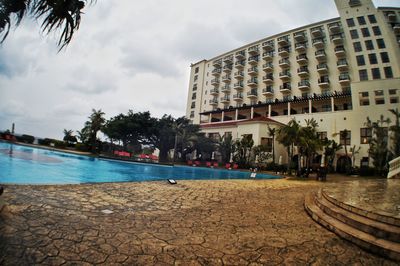 Buildings by swimming pool in city against sky