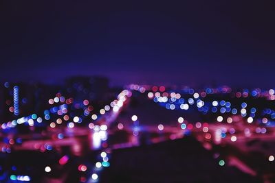 Defocused image of illuminated city against sky at night