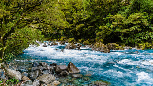 Scenic view of stream flowing through rocks in sea