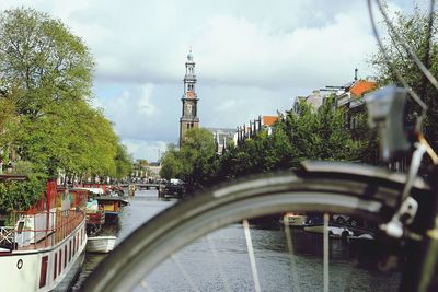 Bridge over river by buildings in city against sky