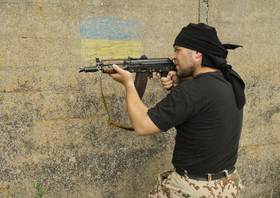 Man holding camera against wall