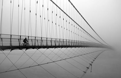 Silhouette man walking on bridge against sky