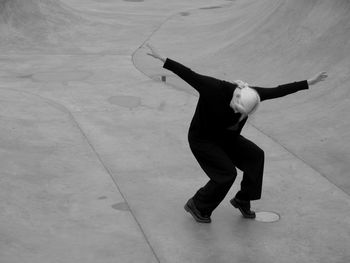 Woman in black dancing on the grey concrete 