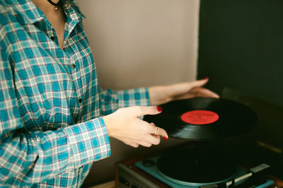 Midsection of young woman holding vinyl record while standing at home