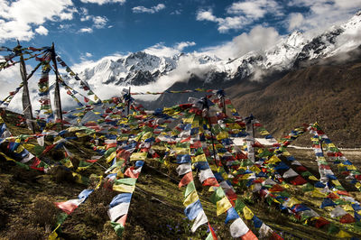 Multiple strings of tibetan prayer flags strung between upright poles on a hillside in nepal