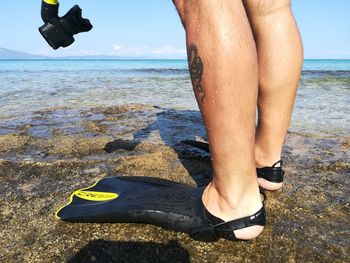 Low section of person on beach against sea