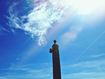 Low angle view of bird perching against blue sky