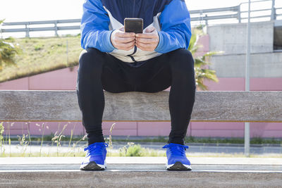 Young man sitting in the park consulting his mobile phone to do sports