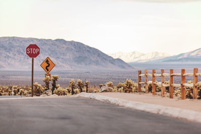 Road sign by mountains against sky