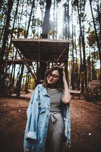 Portrait of woman standing by tree in forest