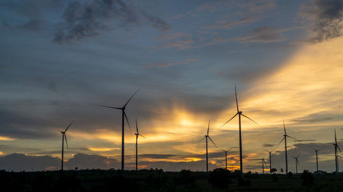 Silhouette of wind turbine against sky during sunset